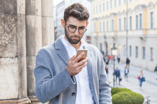 Germany, Munich, portrait of young businessman using cell phone in the city