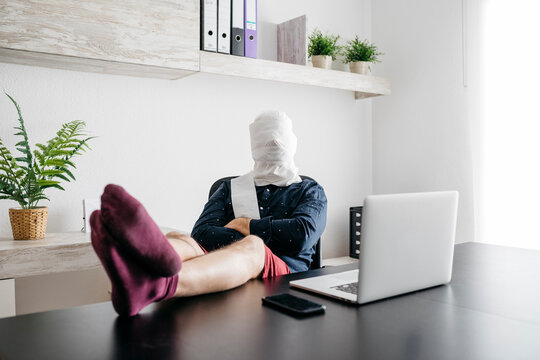 Man working at home with his head covered in toilet paper