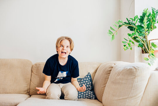 Boy romping around on couch in living room at home