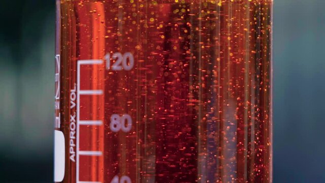 Close up orange emulsion in beaker bubles slowmotion 100fps