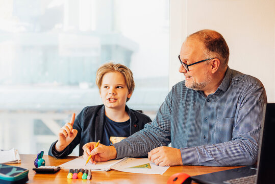 Father helping son doing homework at desk