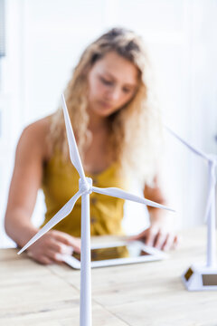 Wind turbine model and woman with digital tablet in the background in an office