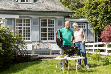 Happy senior couple having a barbecue in garden of their home