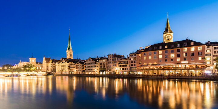 Switzerland, Canton of Zurich, Zurich, River Limmat and old town buildings along illuminated Limmatquai street at dusk