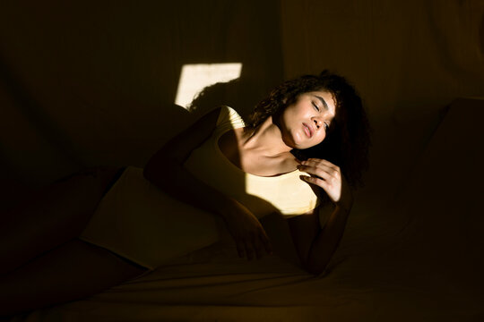 Portrait of attractive young woman lying in bed in sunlight