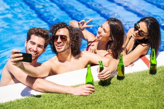 Young man taking selfie with friends at poolside during sunny day - Powered by Adobe