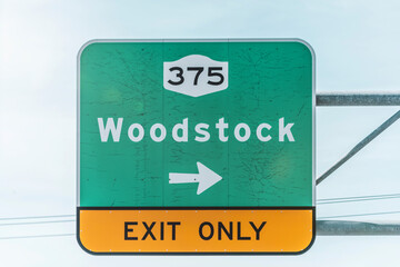 Low angle view of exit road sign at highway against sky