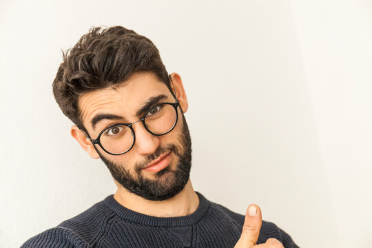 Portrait of doubting young man with beard and glasses