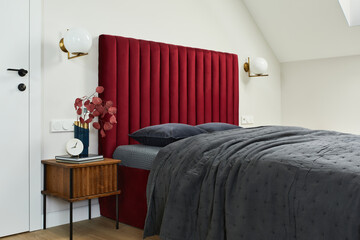 Minimalistic elegant bedroom interior with red bed, grey bedclothes and wooden furniture. Glamour...