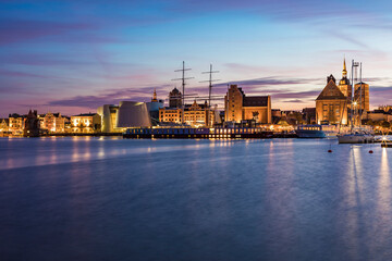 Germany, Mecklenburg-Western Pomerania, Stralsund, Waterfront of coastal town at dusk with sailing ship and Ozeaneum in background