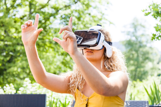 Young blond woman using virtual reality glasses outdoors
