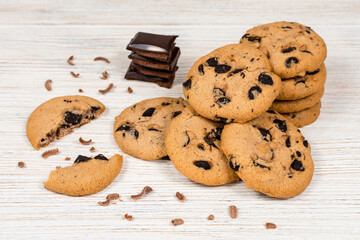 Delicious chocolate chip cookies on a white wooden table with pieces of chocolate.