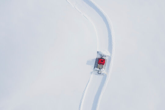 Austria, Tyrol, Galtuer, view to ski slope and snow groomer in winter, aerial view