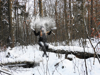 Zimą dziewczyna w lesie rzuca śniegiem