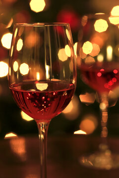 Rose wine in shiny wineglass in front of Christmas tree