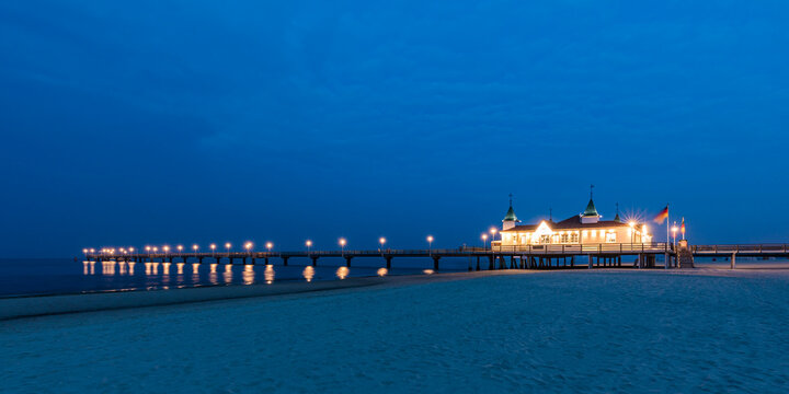 Germany, Mecklenburg-Western Pomerania, Heringsdorf, Sandy coastal beach at dusk with illuminated pier in background