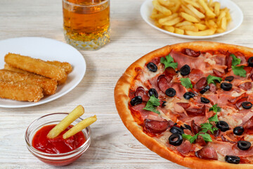 Fast food. Pizza on a platter close-up on a white wooden table with ketchup, juice, sauce and potatoes.