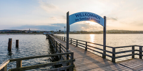 Germany, Mecklenburg-Western Pomerania, Heringsdorf, Welcome sign over empty wooden pier at sunset