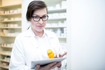 Portrait of pharmacist with tablet and medicine in pharmacy