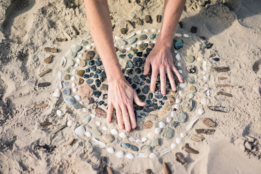 Mature woman making a heart from seashells on the beach