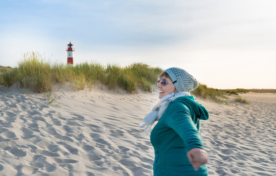 Germany, Sylt, North Sea, woman strolling on sandy beach