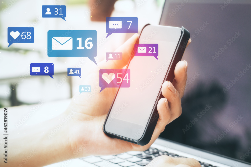 Poster close up of hand using smartphone and laptop with social media icons on blurry background. communica
