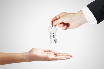 Close up of businessman handing keys on white background. Housing, property, investment and purchase concept.