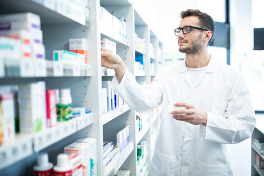 Pharmacist taking medicine from shelf in pharmacy