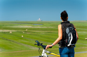 Germany, Schleswig-Holstein, Sankt Peter-Ording, woman with bicycle looking at distance
