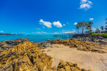 Australia, Queensland, Airlie Beach, Blue sky over rocky coastal beach of Coral Sea