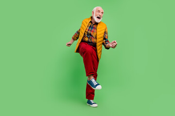 Photo of pretty funny mature man dressed yellow waistcoat smiling dancing isolated green color background
