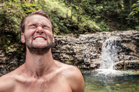 Germany, Upper Bavaria, Bavarian Prealps, lake Walchen, young man is making a face in a cold torrent