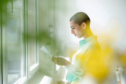 Businesswoman reading papers at the window in loft office