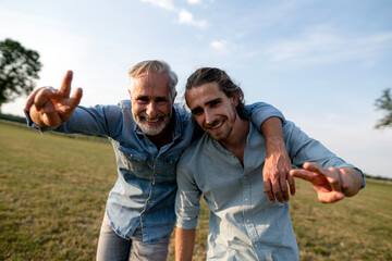 Portrait of happy father with adult son on a meadow in the countryside