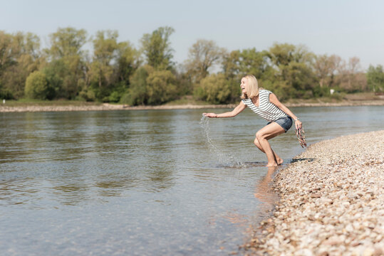 Happy mature woman splashing in a river