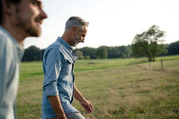 Happy father with adult son on a meadow in the countryside