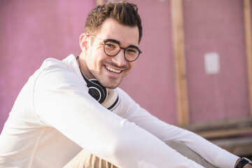 Portrait of happy young man in front of pink wall