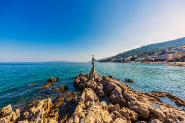 Maiden with the seagull at coast of Adriatic Sea against blue sky