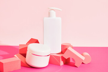 Fototapeta na wymiar white mockup jar of cream and bottle with dispenser on a pink podium on a pink background,