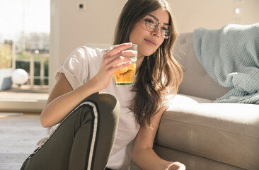 Young woman sitting on the floor at home with a drink
