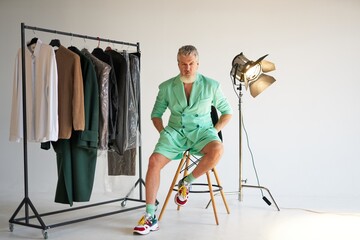 Studio shot of cool middle aged man with beard wearing stylish colorful outfit looking at camera...