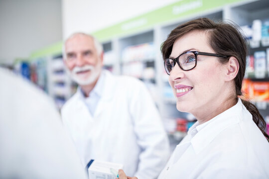 Smiling pharmacist with colleague in pharmacy