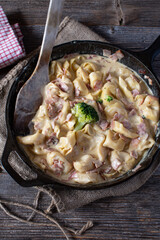 Tortellini in cream sauce with italian ham and parmesan cheese in a rustic cast iron pan