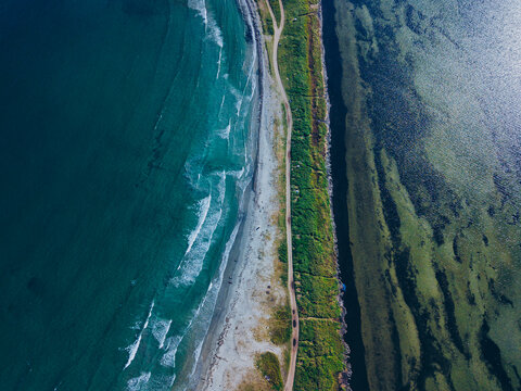 Aerial view of isthmus and dirt road stretching along coast of Krabbe Peninsula
