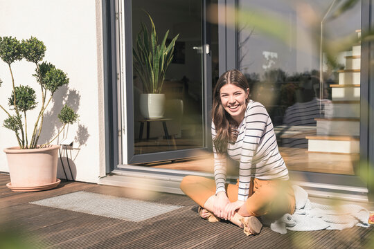 Portrait of laughing young woman sitting on terrace at home