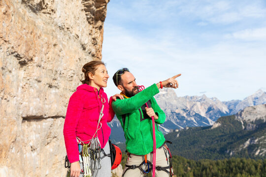 Italy, Cortina d'Ampezzo, couple with climbing equipment looking at view an talking in the Dolomites mountains