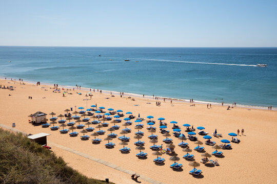 Sunbeds and parasols at beach during summer, Albufeira, Algarve, Portugal