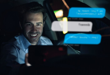 Smiling businessman using cell phone for messaging i in car at night