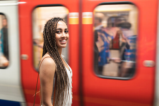 Portrait of smiling young woman waiting at subway station platform, London, UK