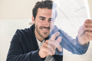 Young businessman in office holding foil of a blueprint